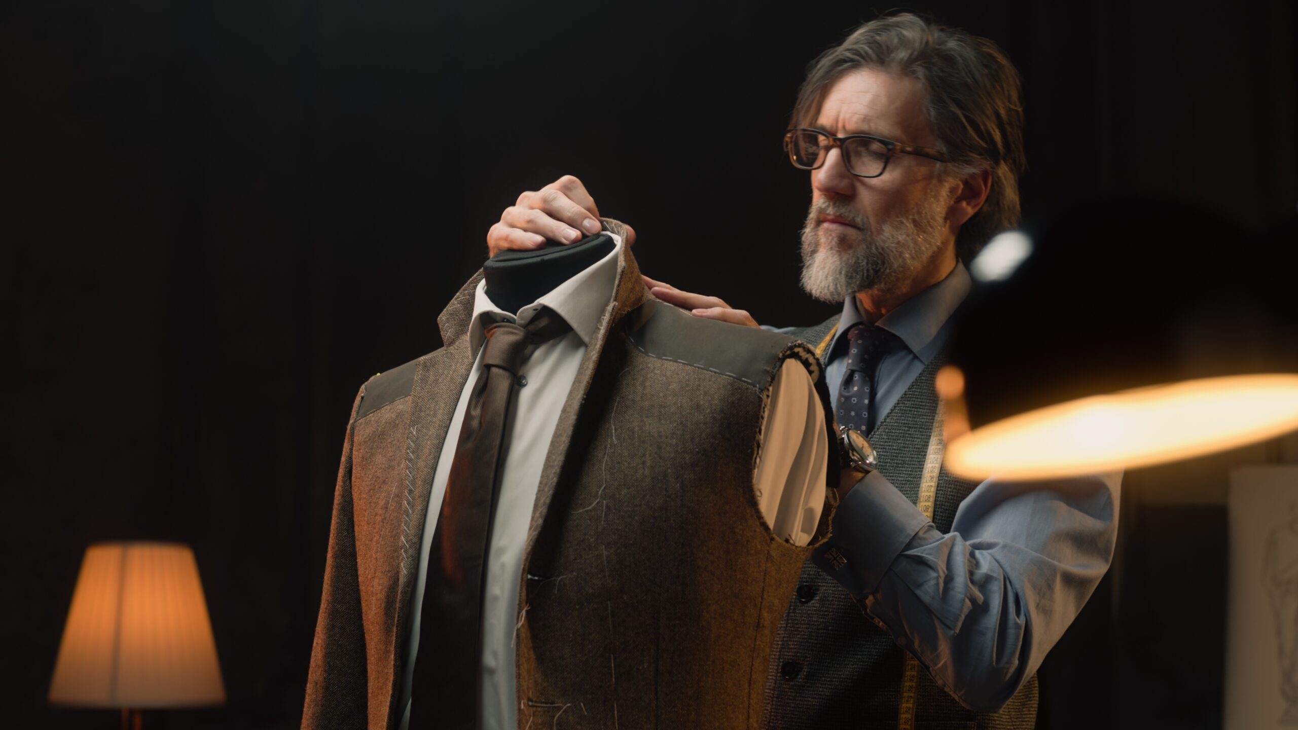 Ein Maßschneider steckt ein Jacket vom Kunden ab