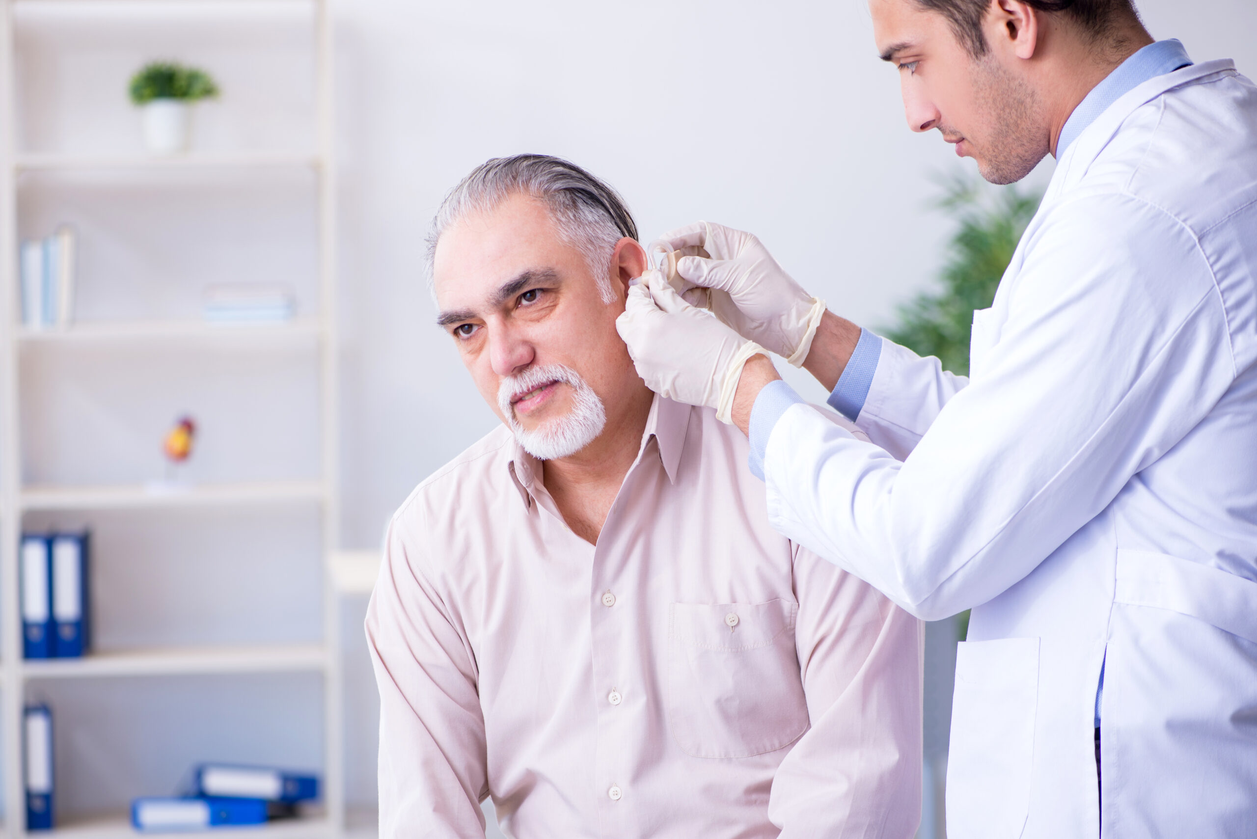 Hörakustiker bei der Anprobe eines Hörgerätes für einen Patienten