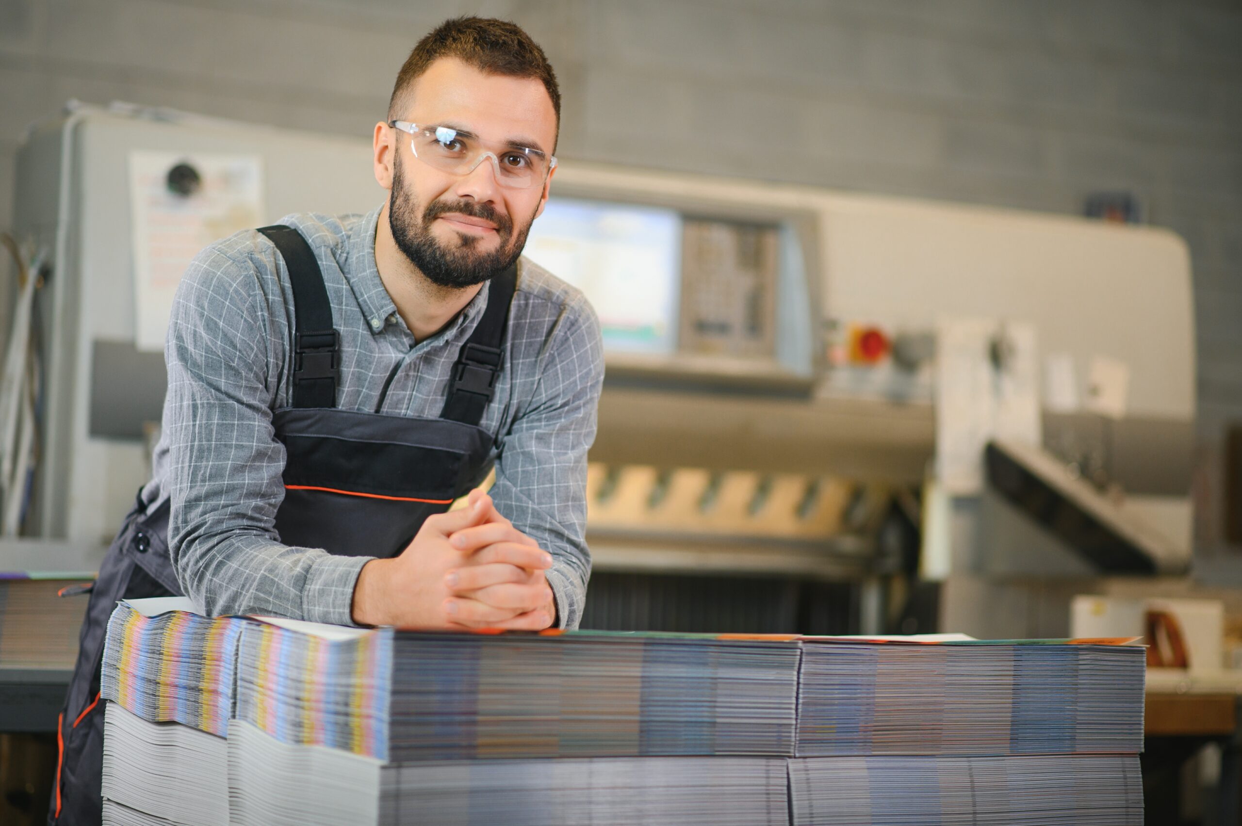 Medientechnologe steht an einer Druckermaschine in einer Druckerei